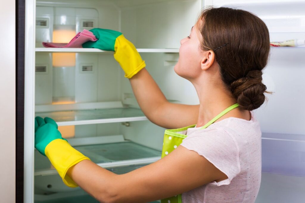 Người đang vệ sinh bên trong tủ lạnh bằng khăn sạch.