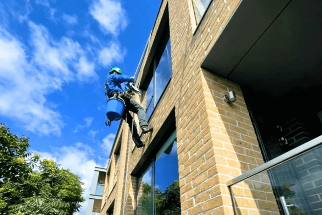 Nhân viên vệ sinh tường bằng phương pháp đu dây, làm sạch bề mặt ở độ cao an toàn và hiệu quả.