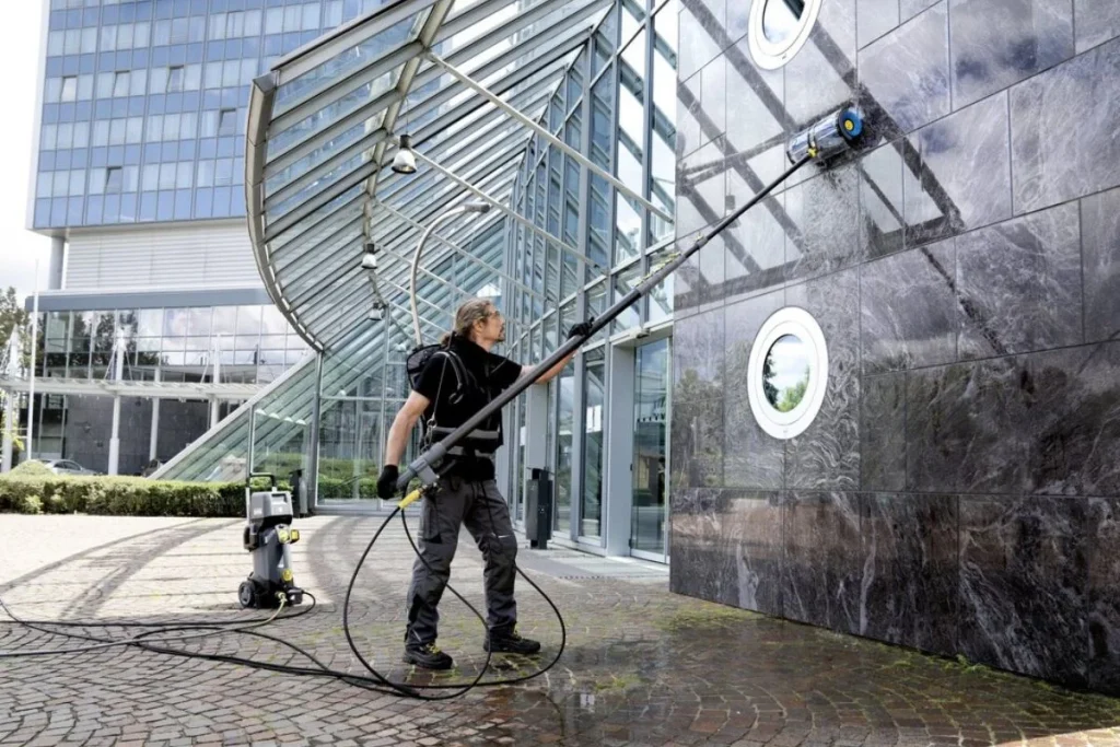 Nhân viên đang vận hành máy chà công nghiệp để vệ sinh tường bê tông trong một công trình lớn.