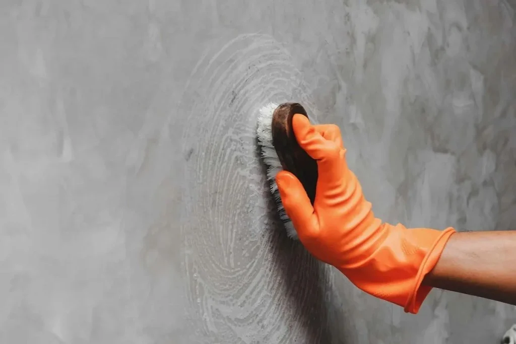 Hình ảnh quá trình vệ sinh tường bê tông, sử dụng vòi xịt áp lực cao làm sạch bề mặt.